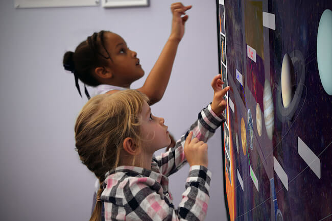 Due bambine usano un display interattivo Promethean per studiare il sistema solare